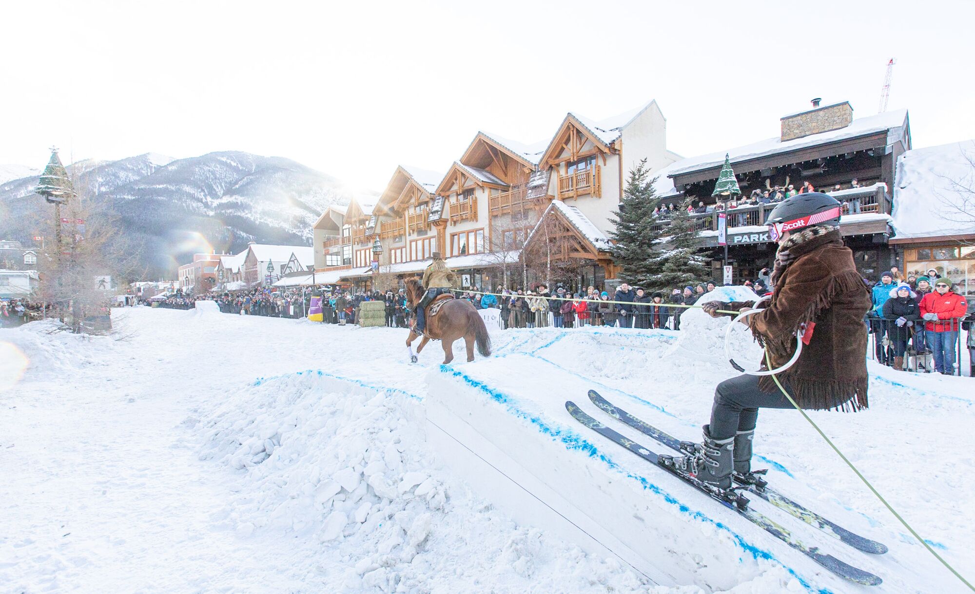 A skier performs a trick while being drawn by a horse during Snow Days Skijoring event on Banff Avenue